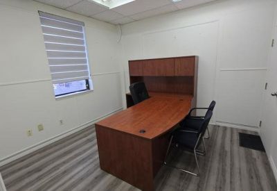 Private office suite featuring a wooden desk with hutch and grey wood-style flooring.