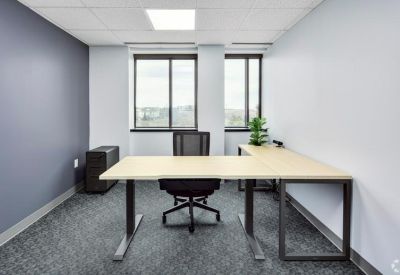 L-shaped wooden desk in a private office with grey feature wall.