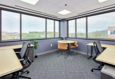Corner office with wrap-around windows and a small circular meeting table.