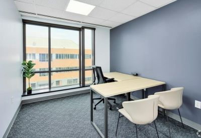 Minimalist private office with L-shaped desk and white guest chairs.