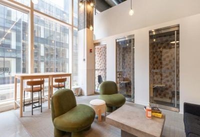 Breakout area with olive green velvet chairs, a coffee table, and high-top seating by a window.