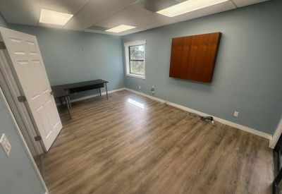 Spacious private office with wood-style flooring and a light blue accent wall.