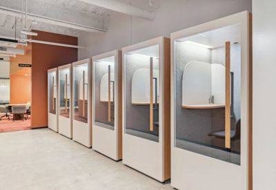 Sleek row of private white phone booths with glass doors for quiet calls.