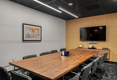 Professional meeting room with a large wood table, black chairs, and a wall-mounted TV.