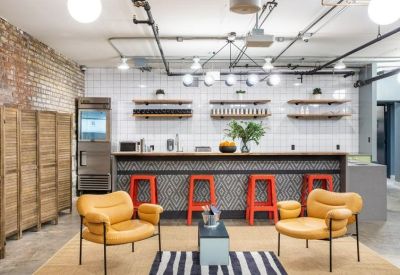 Kitchen and breakout area with a pattern-fronted bar, red stools, and yellow armchairs.