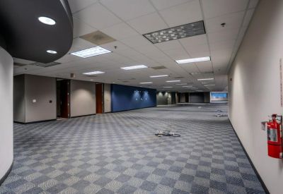 Spacious open-plan office floor with checkered gray carpeting and a blue accent wall.