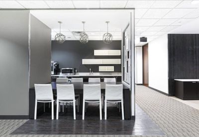 Modern communal kitchen and dining area with pendant lighting and white seating.