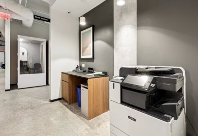 Functional print station area with a large Xerox machine and a wooden supply desk.