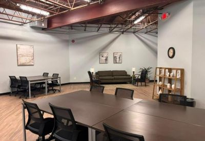 Open office area with several dark wood meeting tables and a cozy lounge nook.