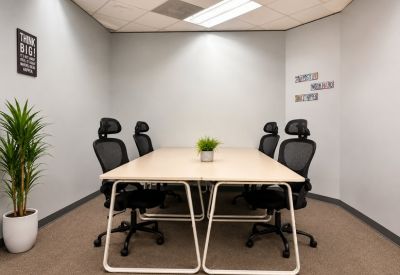 Private meeting room with a light wood table and ergonomic black chairs.