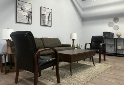 Modern lounge area featuring a brown sofa, leather armchairs, and industrial ceilings.