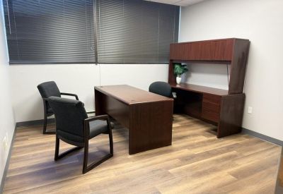 Private office with a dark wood L-shaped desk, hutch, and two guest chairs.