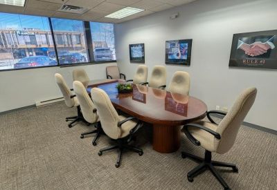 Conference room featuring a large oval wooden table and eight cream-colored rolling chairs.