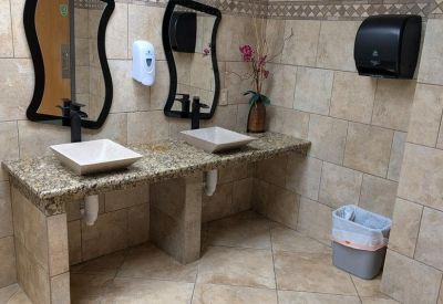 Restroom with double square vessel sinks on a granite countertop and wavy-framed mirrors.