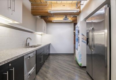 Sleek office kitchen with stainless steel appliances and white cabinetry.