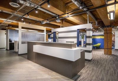 Modern reception desk with clean white finishes and industrial ceiling details.