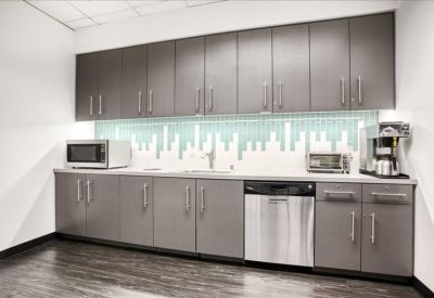 Modern office kitchen with grey cabinetry and a skyline motif backsplash.