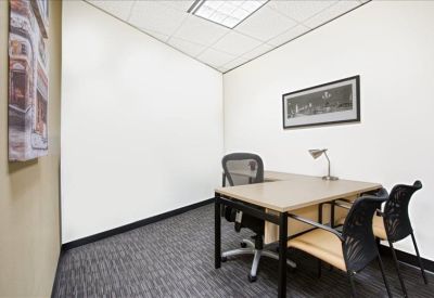Private windowless office suite with a wood-top desk and black mesh chairs.