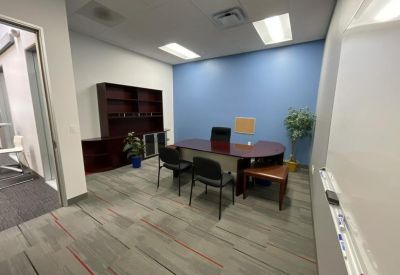 Private executive office suite with a dark wood desk, matching bookshelf, and a blue accent wall.