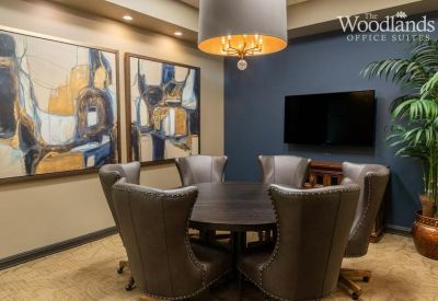 Small meeting room with a round table, grey leather chairs, and abstract art.