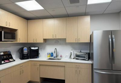 Communal kitchen with light wood cabinetry, stainless steel appliances, and a coffee station.