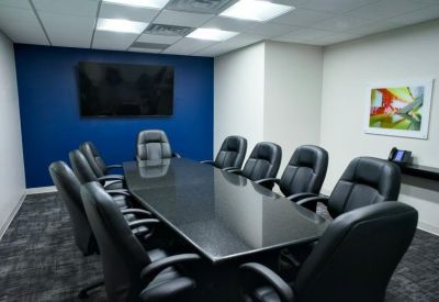 Conference room featuring a dark wood table, leather chairs, and a blue accent wall.