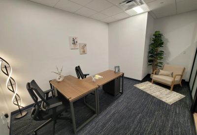 Internal two-person office with L-shaped desks and a small seating area.