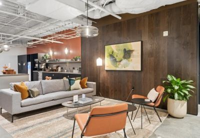 Spacious communal lounge with a grey sofa, leather armchairs, and a wood-paneled feature wall.