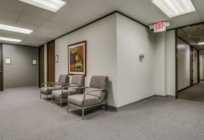 Quiet waiting area with three cushioned armchairs and a piece of framed wall art.