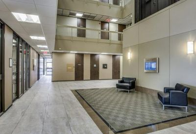 Spacious multi-level atrium lobby with black leather armchairs and tiled flooring.