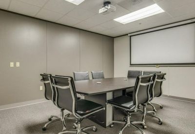 Modern conference room featuring a large wood table and professional black rolling chairs.