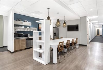 Modern breakroom with a communal dining table and kitchen amenities.