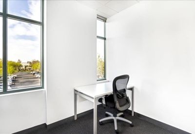 Bright private corner office with a white desk and large windows.