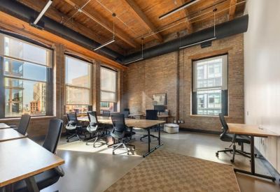 Sunlit open-plan office with exposed brick and timber ceilings.