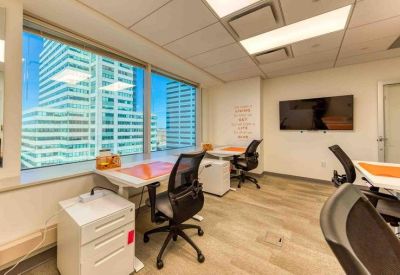 Bright private office featuring a corner window and dual workstations.