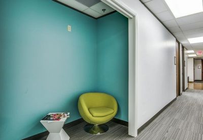 Private nook with a teal feature wall and a bright yellow swivel chair.