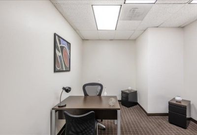Private office with a dark wood desk and framed abstract wall art.