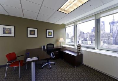 Bright private corner office with a dark wood L-shaped desk and expansive city skyline views.
