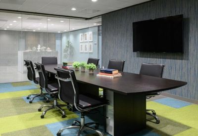 Professional meeting room featuring a dark wood table, black ergonomic chairs, and a wall-mounted screen.