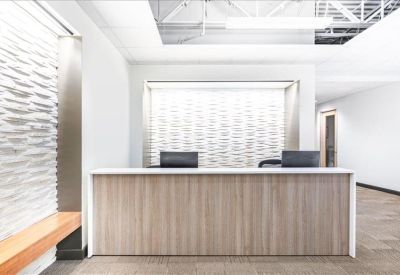 Sleek reception area featuring a wood-panelled desk and textured feature wall.