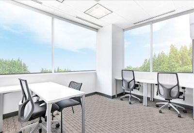 Bright corner office with floor-to-ceiling windows and several workstations.