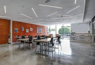 Modern coworking space with white desks and a geometric reception desk.