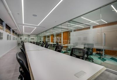 Long communal work table alongside glass-walled meeting rooms.