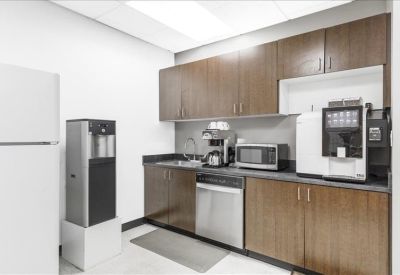Modern communal kitchen with wooden cabinetry, stainless steel dishwasher, and coffee station.