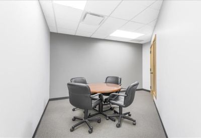 Small meeting room with a round wooden table and four ergonomic chairs.