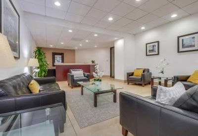 Reception lobby with black leather sofas, glass coffee table, and a dark wood front desk.