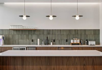 Contemporary kitchen area with a large marble island, dark wood cabinetry, and green tile backsplash.