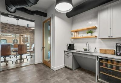 Modern communal kitchen with white cabinetry, open wooden shelving, and a wine fridge.