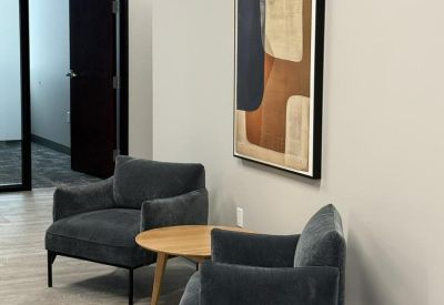 Waiting area featuring two grey velvet armchairs and abstract wall art.