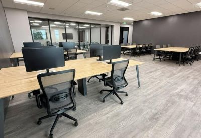Spacious open-plan workspace with multiple light wood desks and ergonomic chairs.